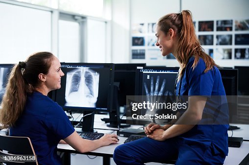Two female healthcare professionals looking at x-ray scans Two female healthcare professionals looking at x-ray scans