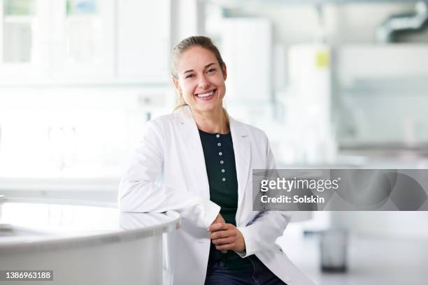 female scientist in lab coat sitting in laboratory - european doctor stock-fotos und bilder