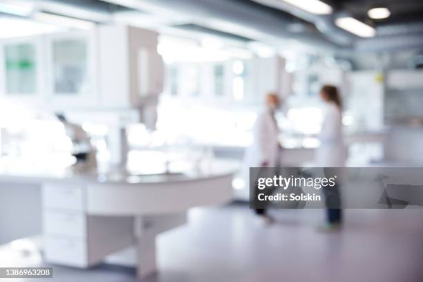 defocused image of laboratory with two scientist - laboratorium stockfoto's en -beelden