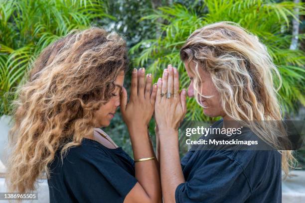 offene multirassische frauen kopf an kopf in namaste-gebetspose im freien - prayer pose greeting stock-fotos und bilder