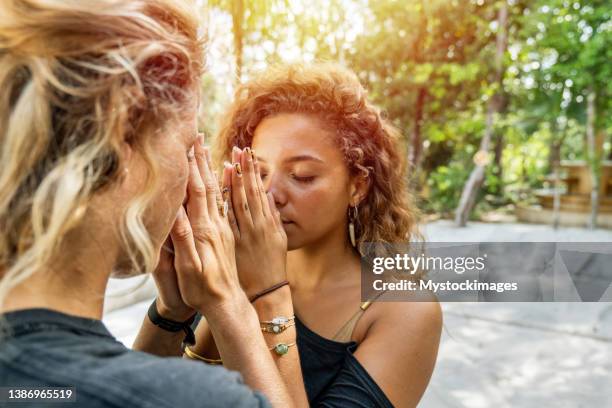 candid multiracial females head to head in namaste prayer pose outdoors - namaste bildbanksfoton och bilder