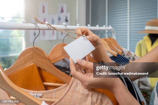 close up of blank price tag paper on a wooden hanger with a t-shirt in the fashion store. - shirt tag stock pictures, royalty-free photos & images