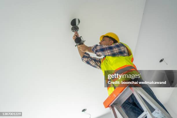 electrician man worker installing ceiling lamp - asian ceiling stock pictures, royalty-free photos & images