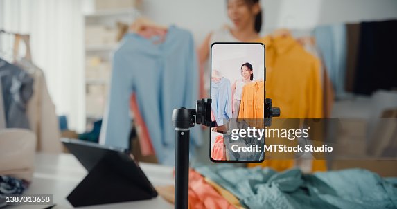 Asian businesswoman live-streamed ecommerce sell clothes at home, beautiful girl using the smartphone and tablet for recording video. Asian businesswoman live-streamed ecommerce sell clothes at home, beautiful girl using the smartphone and tablet for recording video.