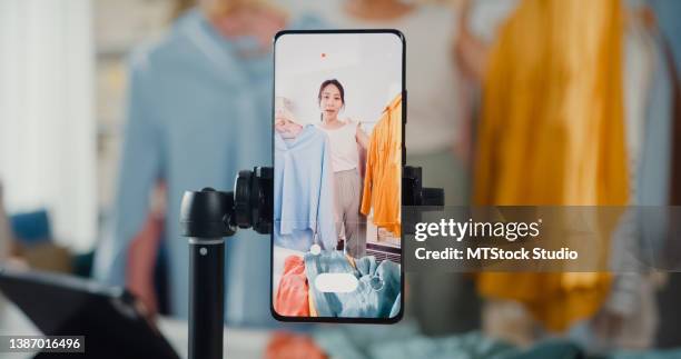 asian businesswoman live-streamed ecommerce sell clothes at home, beautiful girl using the smartphone and tablet for recording video. - live event camera stock pictures, royalty-free photos & images