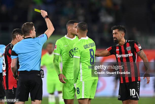 Referee Felix Brych shows the yellow card to Kerem Demirbay of Leverkusen during the Bundesliga match between VfL Wolfsburg and Bayer 04 Leverkusen...