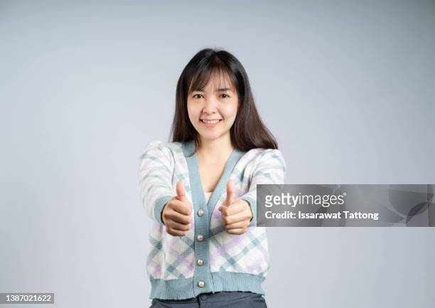 young happy cheerful woman showing thumb up - happy woman thumbs studio ストックフォトと画像