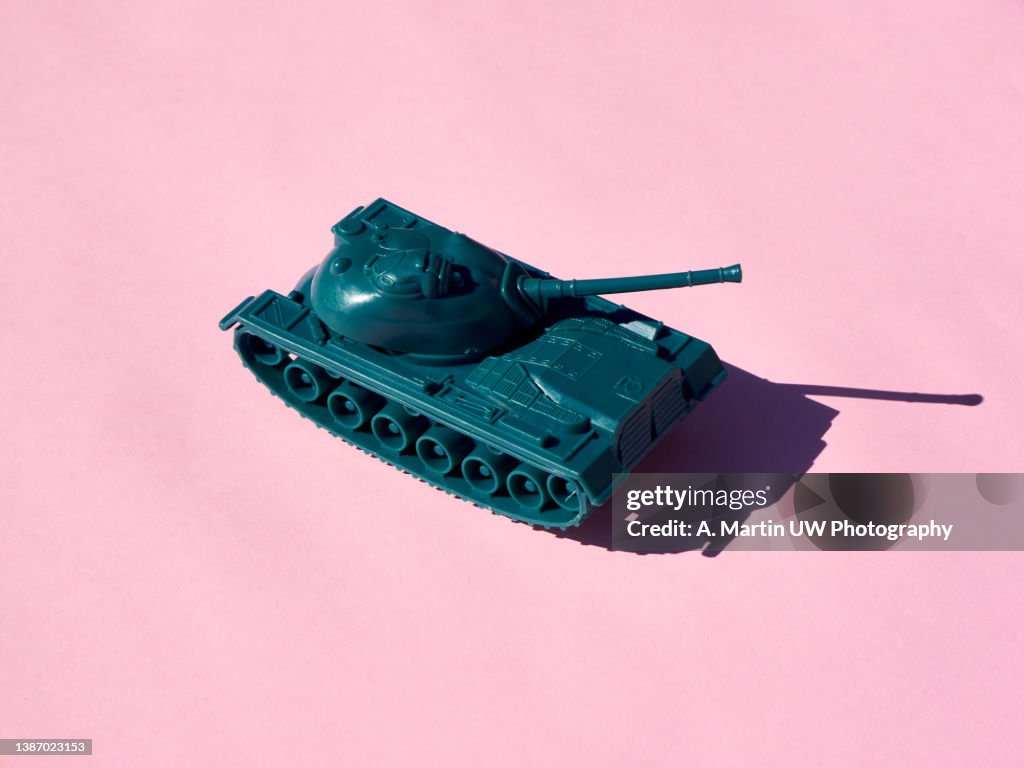 Plastic toy tank isolated on pink background.
