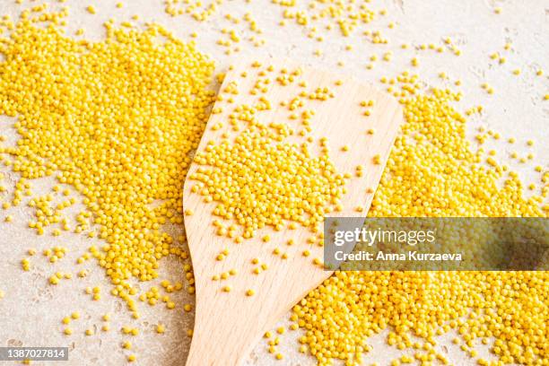 close-up of raw millet in a wooden spoon and on a table, top view - millet stock pictures, royalty-free photos & images