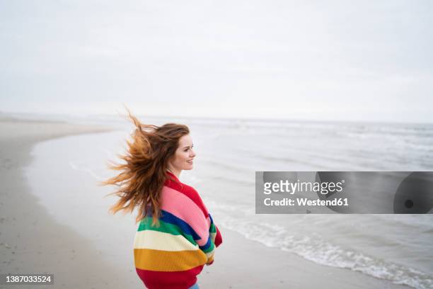 smiling young woman with tousled hair standing at beach - ostfriesiska öarna bildbanksfoton och bilder