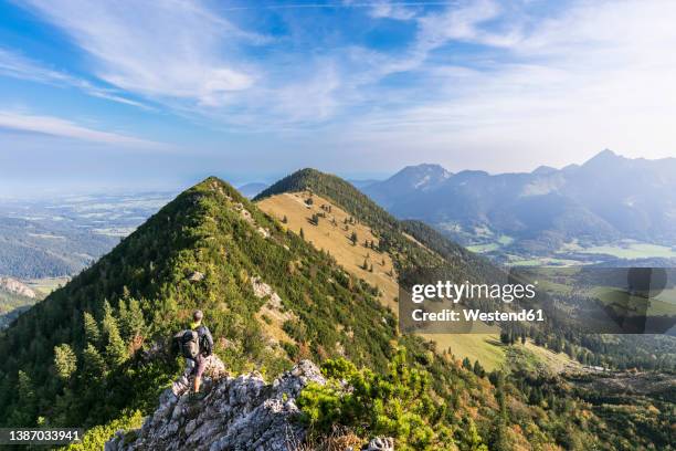 male hiker admiring view from summit of aiplspitz mountain - miesbach stockfoto's en -beelden