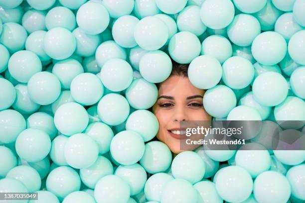smiling woman amidst blue balls - adult ball pit stock pictures, royalty-free photos & images