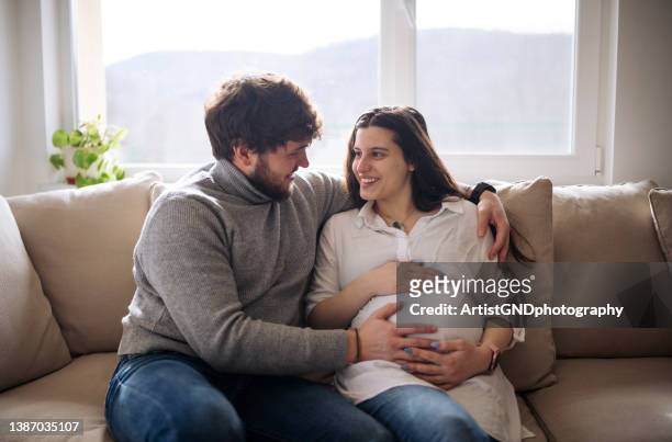 happy couple feeling movements of baby belly of the expectant mother. - husband stock pictures, royalty-free photos & images