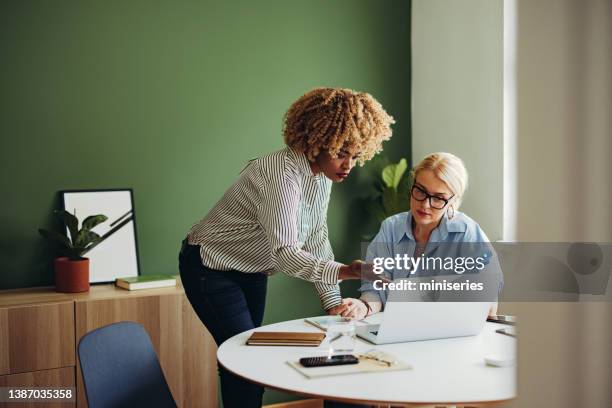 team of two businesswoman working together on a laptop computer - showing laptop stock pictures, royalty-free photos & images