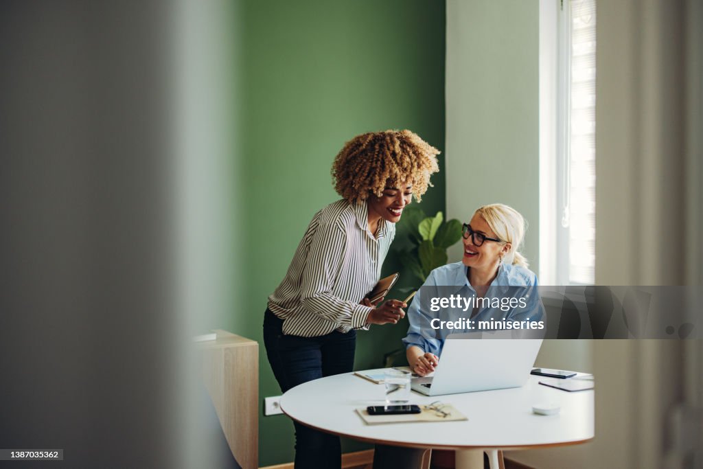 Team von zwei glücklichen Geschäftsfrauen, die zusammen an einem Laptop-Computer arbeiten