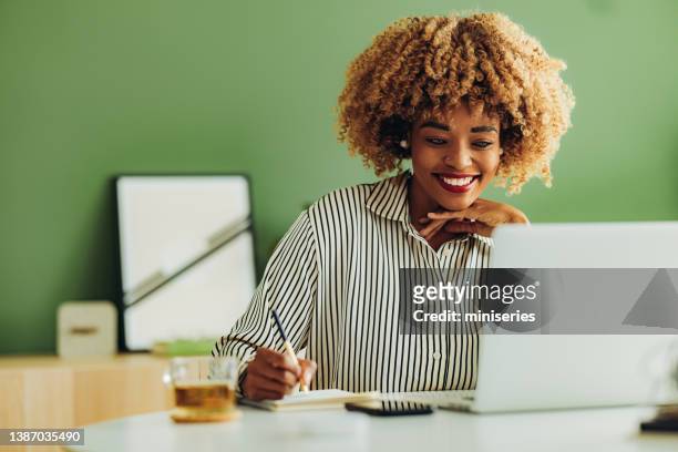 glückliche geschäftsfrau, die in ihrem büro arbeitet - frau am laptop stock-fotos und bilder