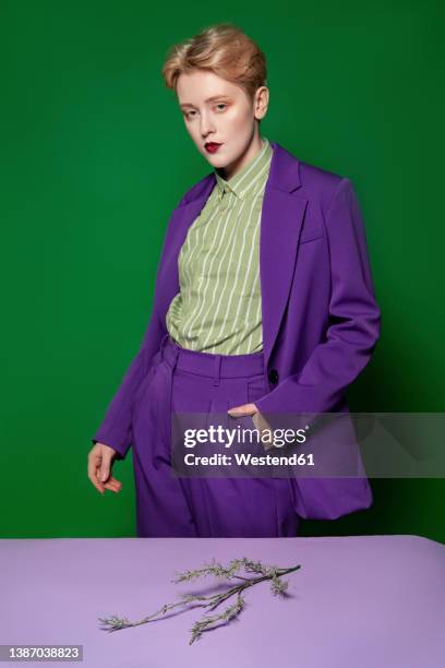 woman with hand in pocket by flower on table at studio - purple blazer stock pictures, royalty-free photos & images