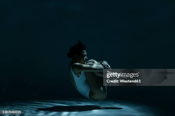 woman in fetal position swimming underwater - position du foetus photos et images de collection