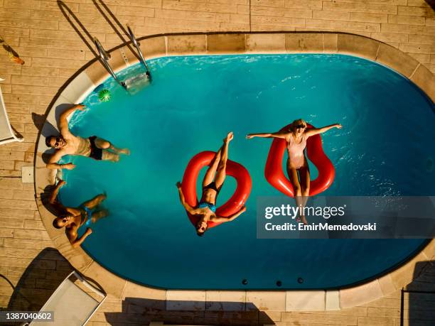 playful friends hanging out at pool party - zonnebank stockfoto's en -beelden