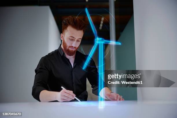 engineer working on digital display by wind turbine at desk in office - engineer cad photos et images de collection
