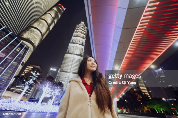 confident young asian woman standing under the glowing pedestrian bridge in downtown shanghai - data trust stock pictures, royalty-free photos & images