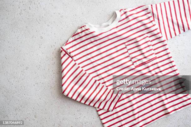 close-up of striped red and white long sleeved t-shirt on concrete background, top view - long sleeve t shirt stock pictures, royalty-free photos & images