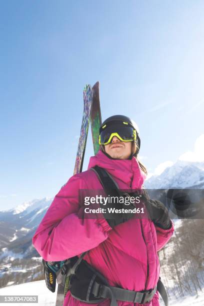 man carrying ski in winter on sunny day - casaco de esqui imagens e fotografias de stock
