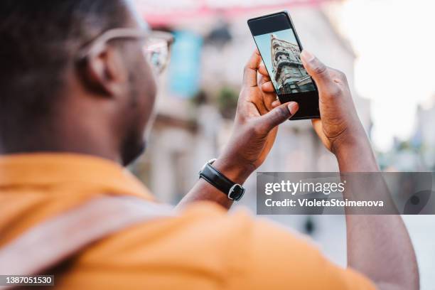 male traveler takes a photo using his smartphone. - fotoberichten stockfoto's en -beelden