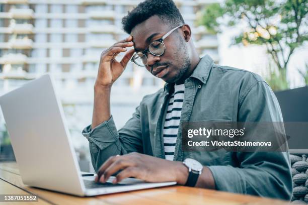 stressed businessman using laptop at sidewalk cafe. - zoom fatigue stock pictures, royalty-free photos & images