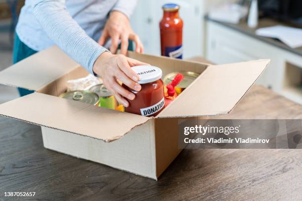 unrecognisable person is filling a box with food to donate people in need - refugee aid stock pictures, royalty-free photos & images