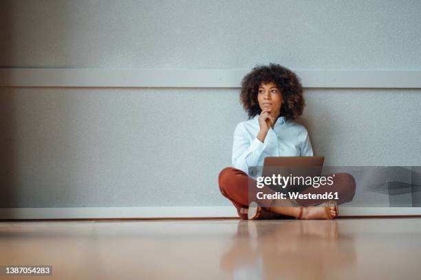 thoughtful businesswoman with laptop sitting on floor at work place - sitting on ground stock pictures, royalty-free photos & images