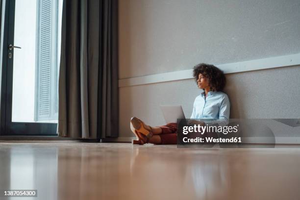 thoughtful businesswoman with laptop at work place - sitting on the floor stock-fotos und bilder