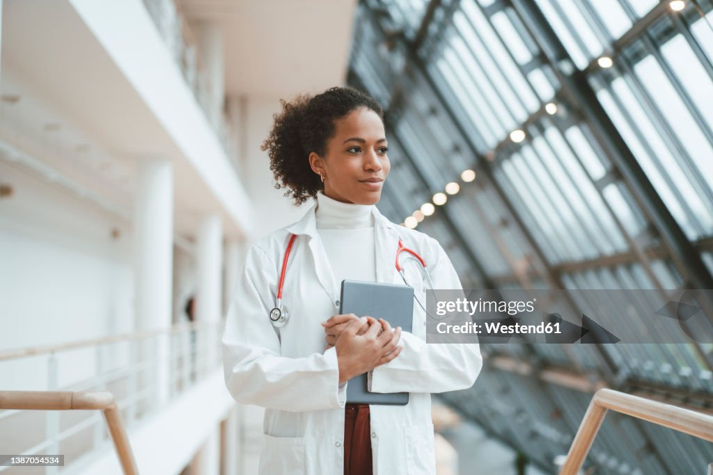 Thoughtful doctor with tablet PC in medical clinic