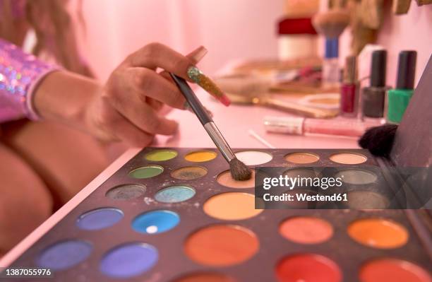 non binary person holding brush on eye shadow palette - drag queen stockfoto's en -beelden