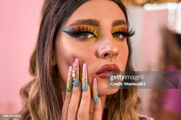 non binary person with make-up touching cheek - drag queen stockfoto's en -beelden