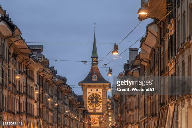 switzerland, canton of bern, bern, street lights and power lines stretching over old town street at dusk with zytglogge clock tower in background - bern clock tower stock pictures, royalty-free photos & images