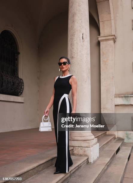 Füsun Lindner seen wearing a black Celine sunglasses, gold earrings from Louis Vuitton, a black with white stripe wide leg overall from Staud, a...