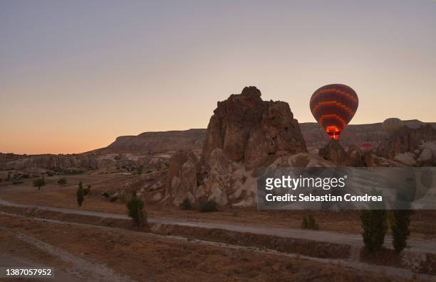 balloons and beautiful sunrise over the rocks in goreme. cappadocia, turkey - cappadocia hot air balloon stock-fotos und bilder