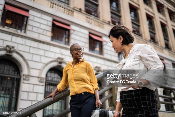 mature businesswomen talking in the city - cup international team stock pictures, royalty-free photos & images