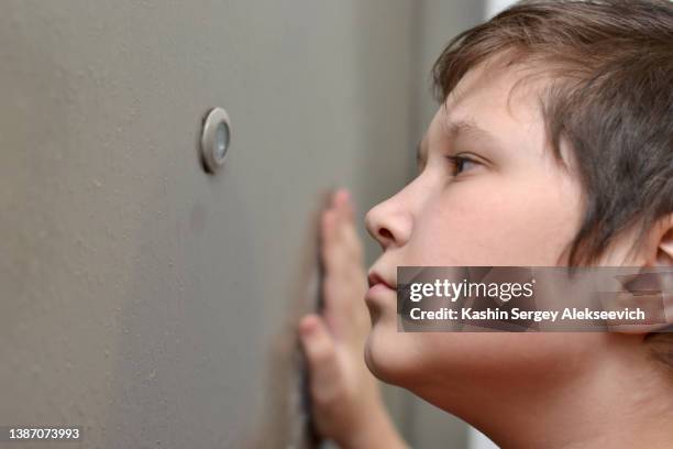 boy looking through a keyhole in a door. - looking through keyhole stock pictures, royalty-free photos & images