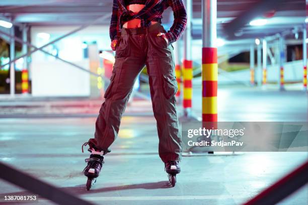 persona non riconosciuta nei pattini a rotelle in piedi nel parcheggio di un garage pubblico - pantaloni militari foto e immagini stock