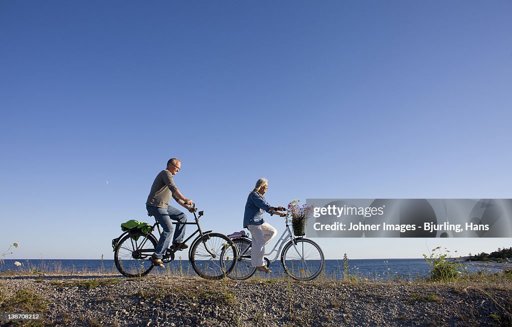 Mature couple riding bicycle on beach