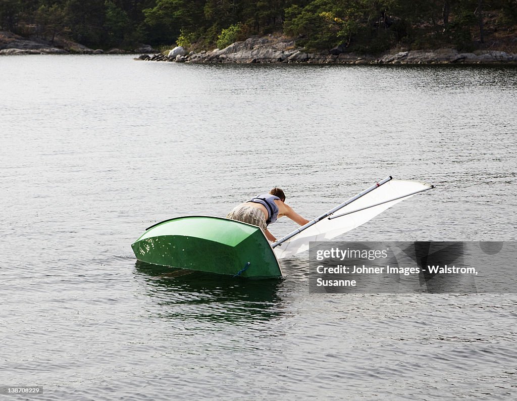 Man and dinghy falling into water