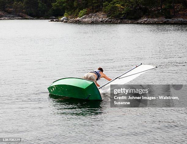 man and dinghy falling into water - fracaso fotografías e imágenes de stock