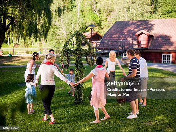 men, women and children dancing in circles - midsummer sweden stock-fotos und bilder