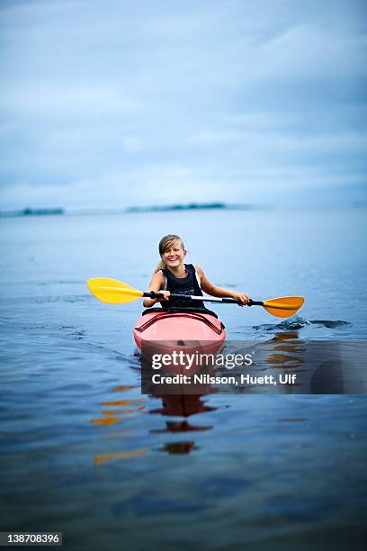 teenage girl rowing canoe on lake, smiling - girl rowing boat photos et images de collection