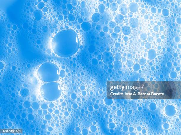 full frame of the bubbles and soap suds in the bathroom on a blue background. - blue bathroom stock-fotos und bilder