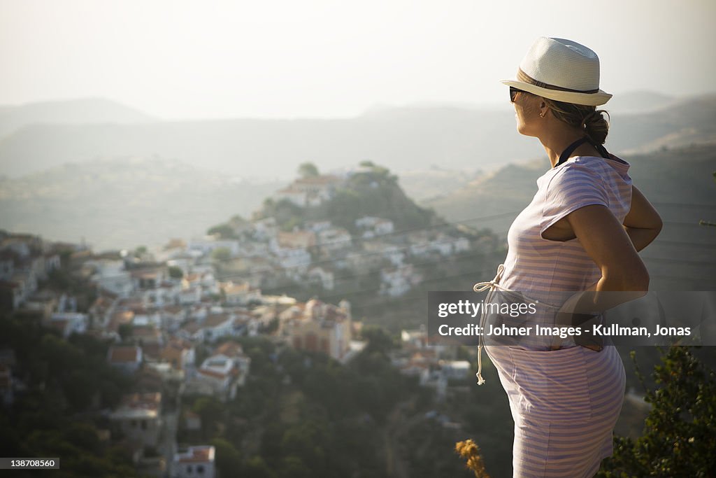 Pregnant woman standing with hand on hip, mountains in background