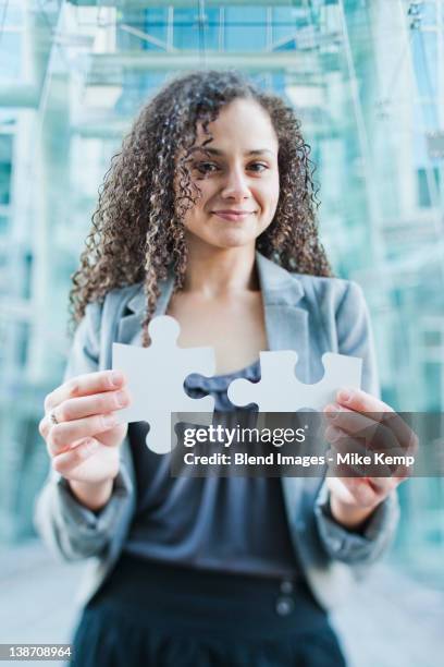 caucasian businesswoman holding jigsaw puzzle pieces - puzzleteile stock-fotos und bilder