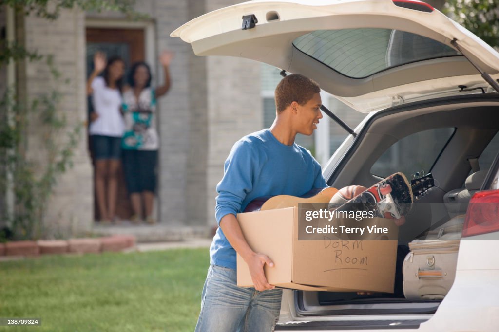 Mixed race teenager loading car for college